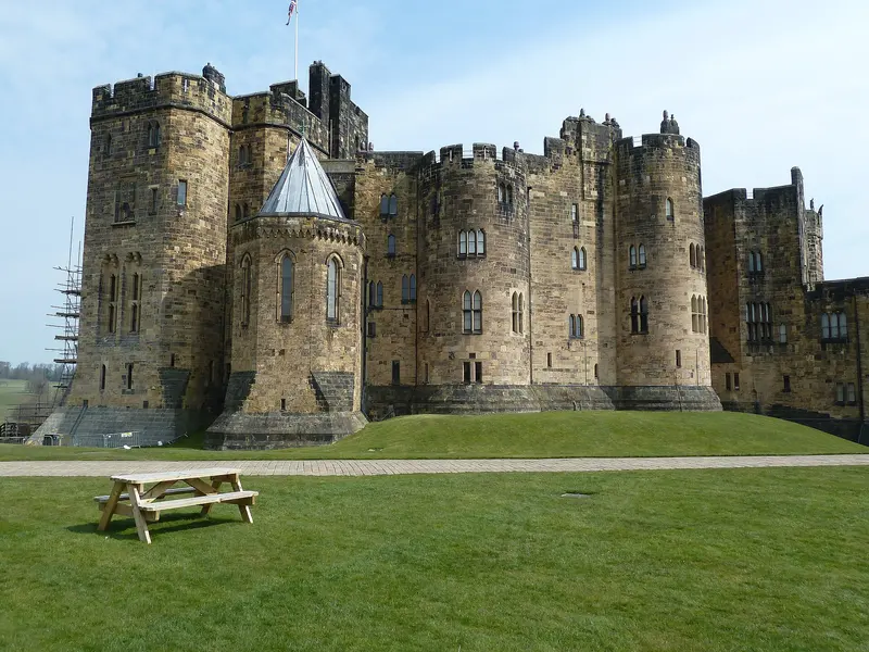 The round towers and battlements of Alnwick Castle above a lawn