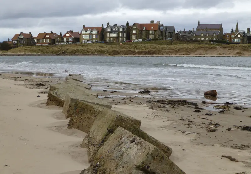 Houses of Alnmouth village above the dunes, seen across the mouth of the River Aln