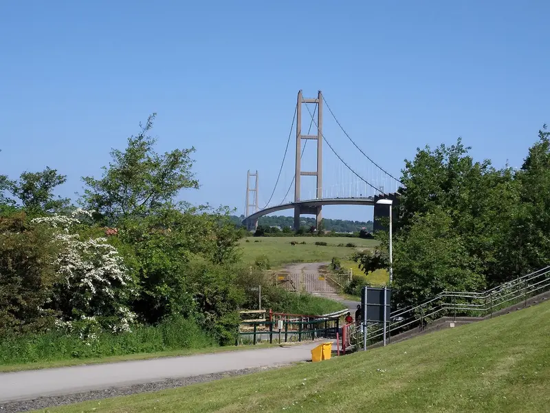 The Humber Bridge's tall towers and suspension cables seen from a grassy path at Hessle