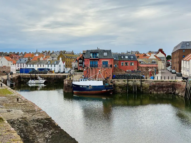 Fishing boats in Dunbar's old harbour, with colourful houses along the quayside behind