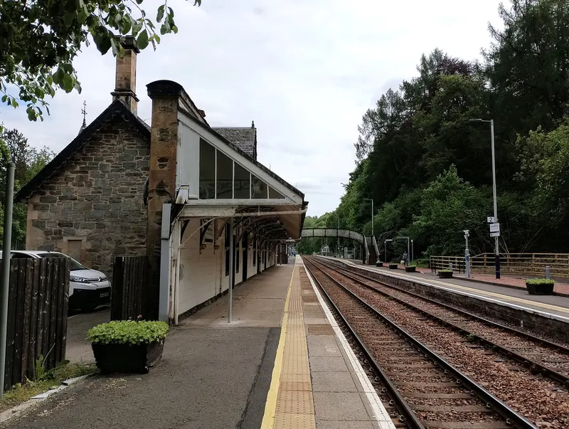 Platform 1 at Dunkeld and Birnam under the station awning, with wooded hillside beyond