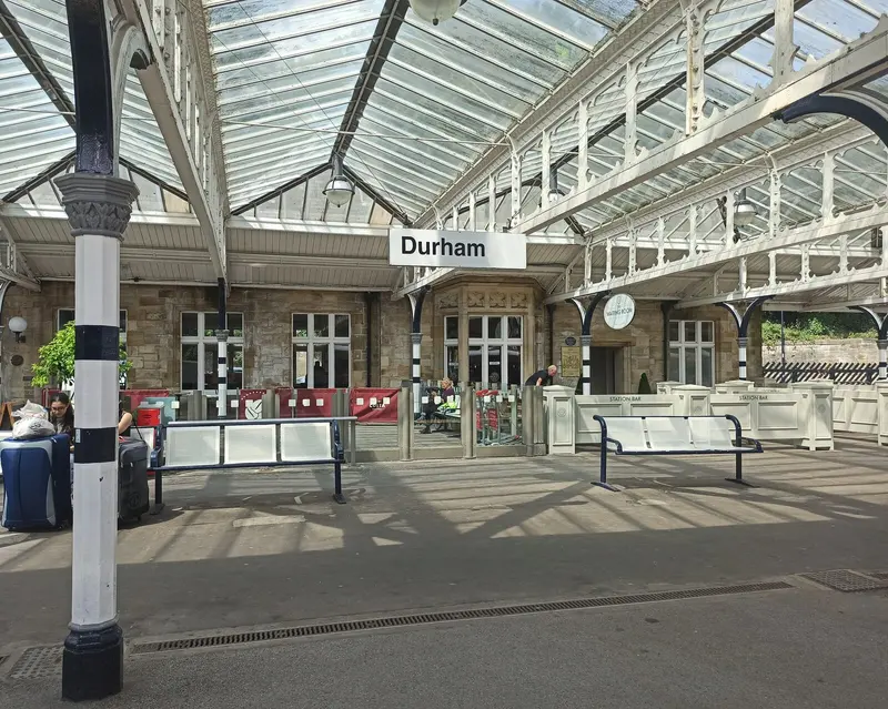 The glazed canopy and stone station building at Durham, with the Durham station sign