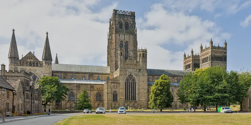 The long nave and central tower of Durham Cathedral seen across a lawn