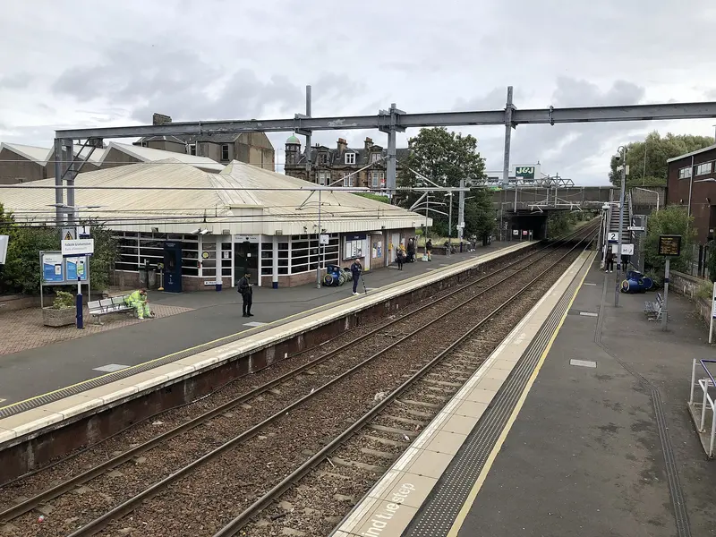Falkirk Grahamston station seen from the footbridge, with the single-storey station building on the left and overhead electric wires above the tracks