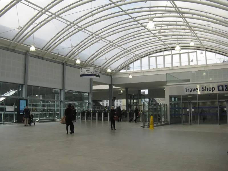 Haymarket's bright modern concourse under a curved white roof, with ticket gates ahead and a travel shop to the right