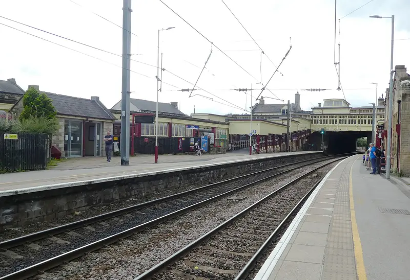 The electrified National Rail platforms at Keighley, with station buildings and the road bridge at the far end