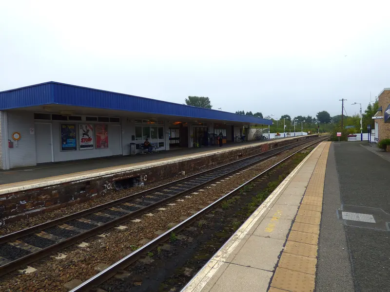 Kirkcaldy station's single-storey 1960s building with a blue canopy along platform 1, seen across the tracks