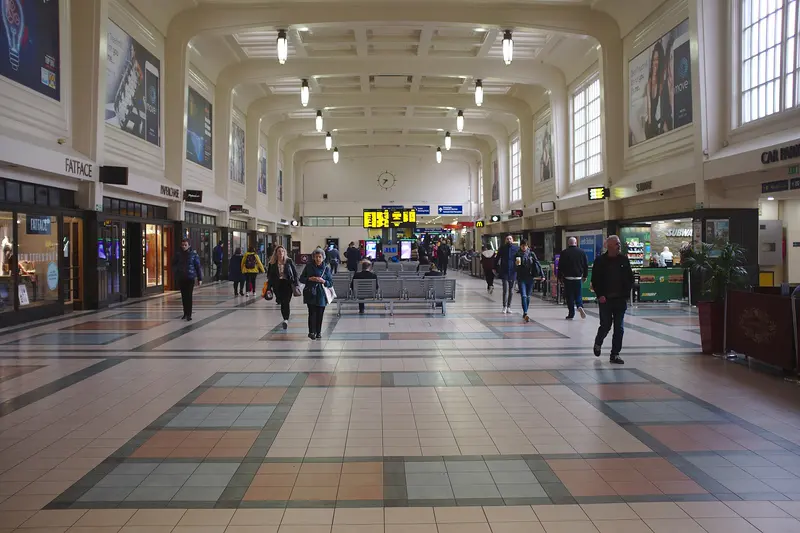 The long art deco north concourse at Leeds station, with a coffered ceiling, tall windows and a patterned tiled floor