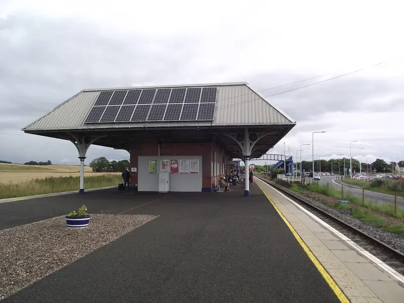 The station building with a wide hipped canopy on Leuchars' island platform, with the footbridge in the distance