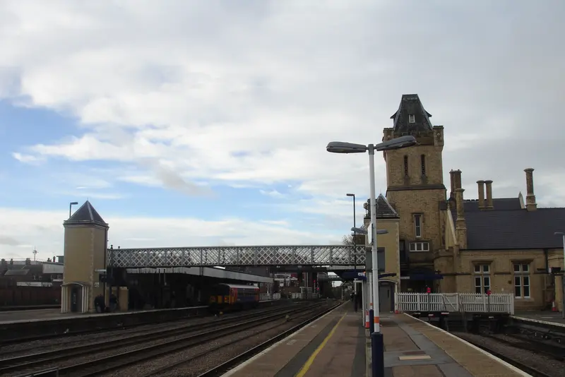 Platforms at Lincoln station with the station's tower, a footbridge and overhead lamps