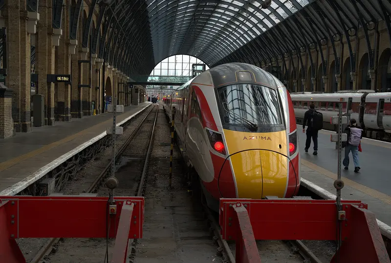An LNER Azuma train waiting at a platform beneath the arched glazed roof of the King's Cross train shed