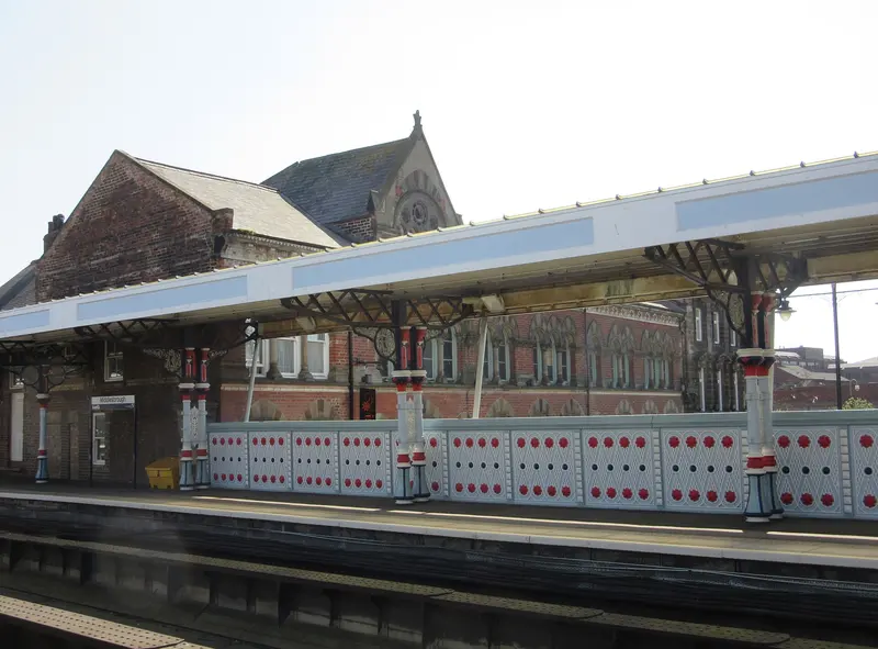 Ornate red and white cast-iron columns and railings under the platform canopy at Middlesbrough station