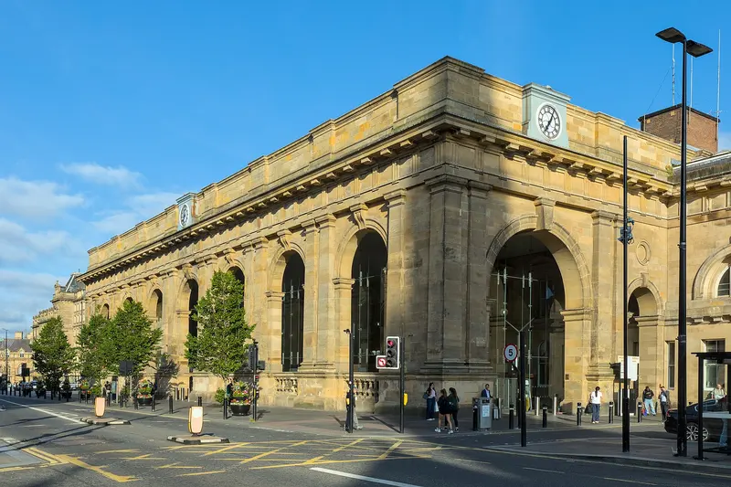 The long sandstone arcade and clock of Newcastle Central station's portico on Neville Street