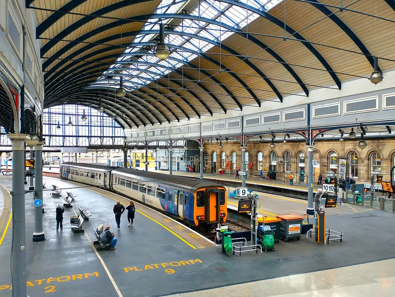 Curved iron and glass train shed over the platforms at Newcastle Central, with a local train waiting