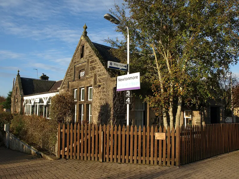 The stone former station building at Newtonmore with a gabled end and a picket fence