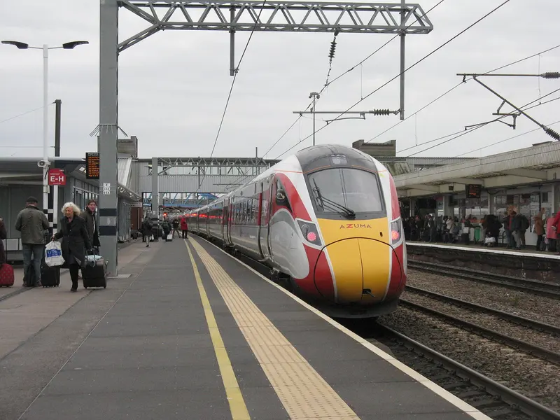 An LNER Azuma train alongside a platform at Peterborough station, with passengers and luggage on the platform