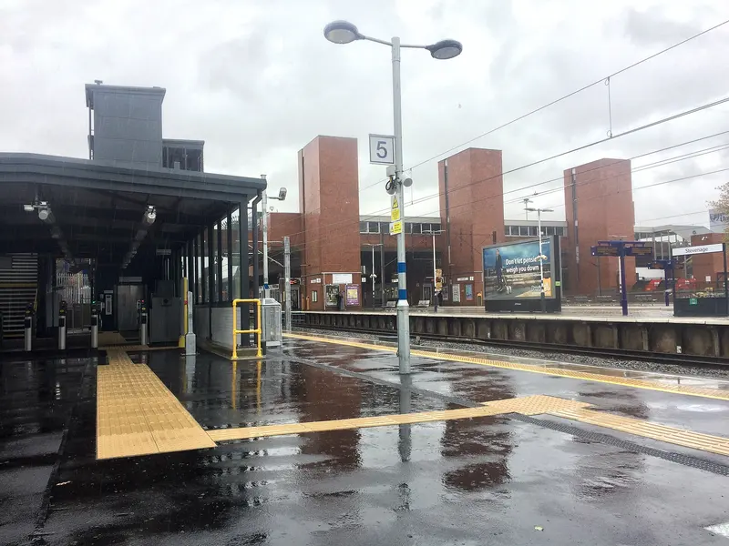 The new platform 5 at Stevenage on a wet day, with a glazed shelter and tactile paving