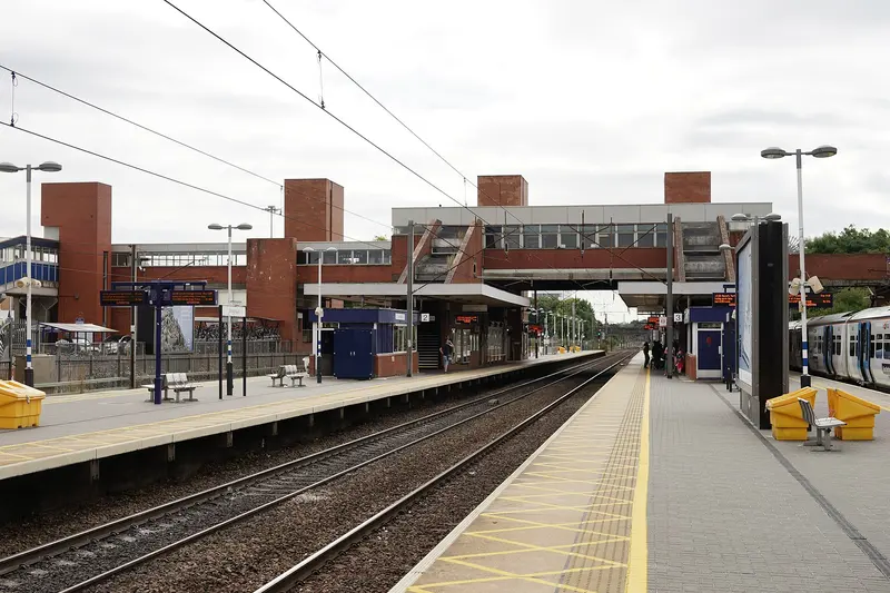 Two island platforms at Stevenage station linked by a brick and glass footbridge with lift towers