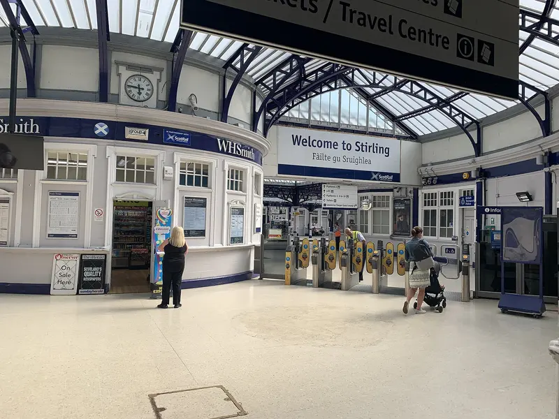 The glazed, horseshoe-shaped concourse at Stirling station with the curved ticket office and ticket gates
