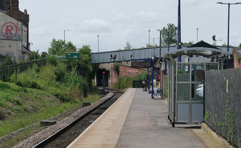A platform at Thornaby station with a glass shelter and a footbridge beyond