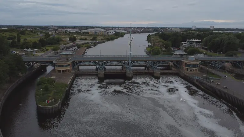 Aerial view of the Tees Barrage across the river, with the Infinity Bridge in the distance