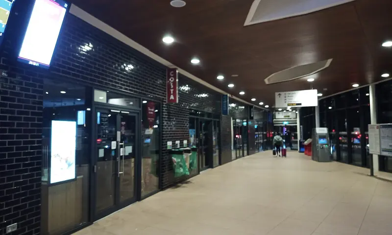 The bright modern concourse of Wakefield Westgate station, with dark tiled walls, departure screens and shop fronts